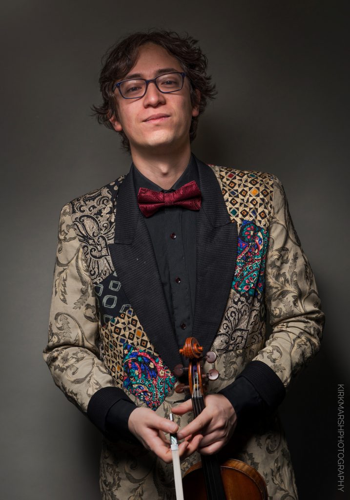 Jeffrey Young headshot with violin and an imperious expression in an elaborate jacket
