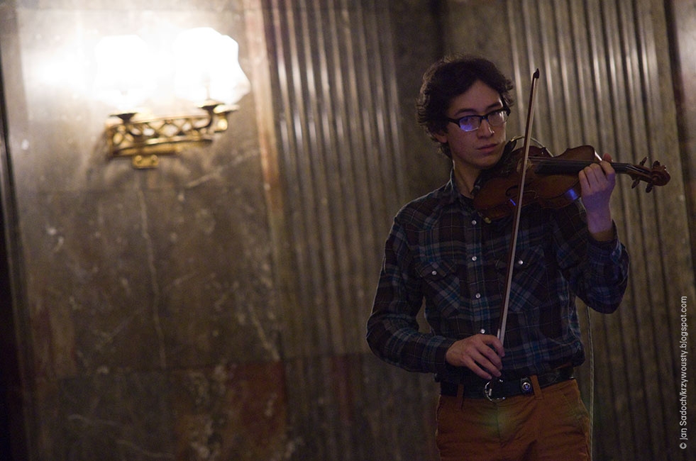 Jeffrey Young performing on violin wearing casual clothes in a marble interior in Poland
