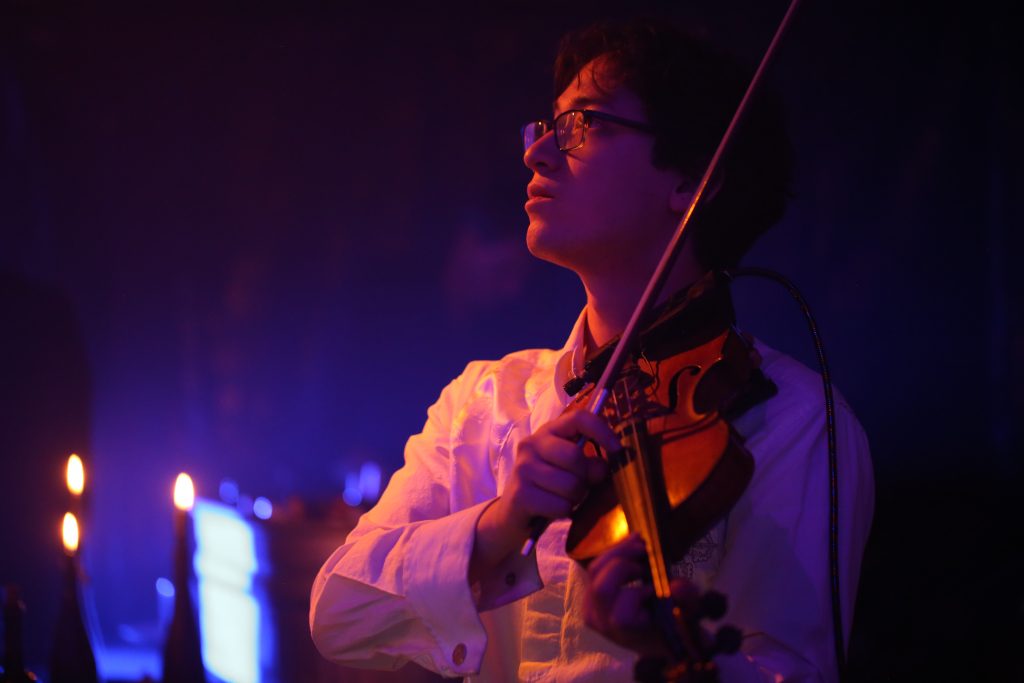 Jeffrey Young performing solo on the violin, looking dreamily upward in atmospheric lighting